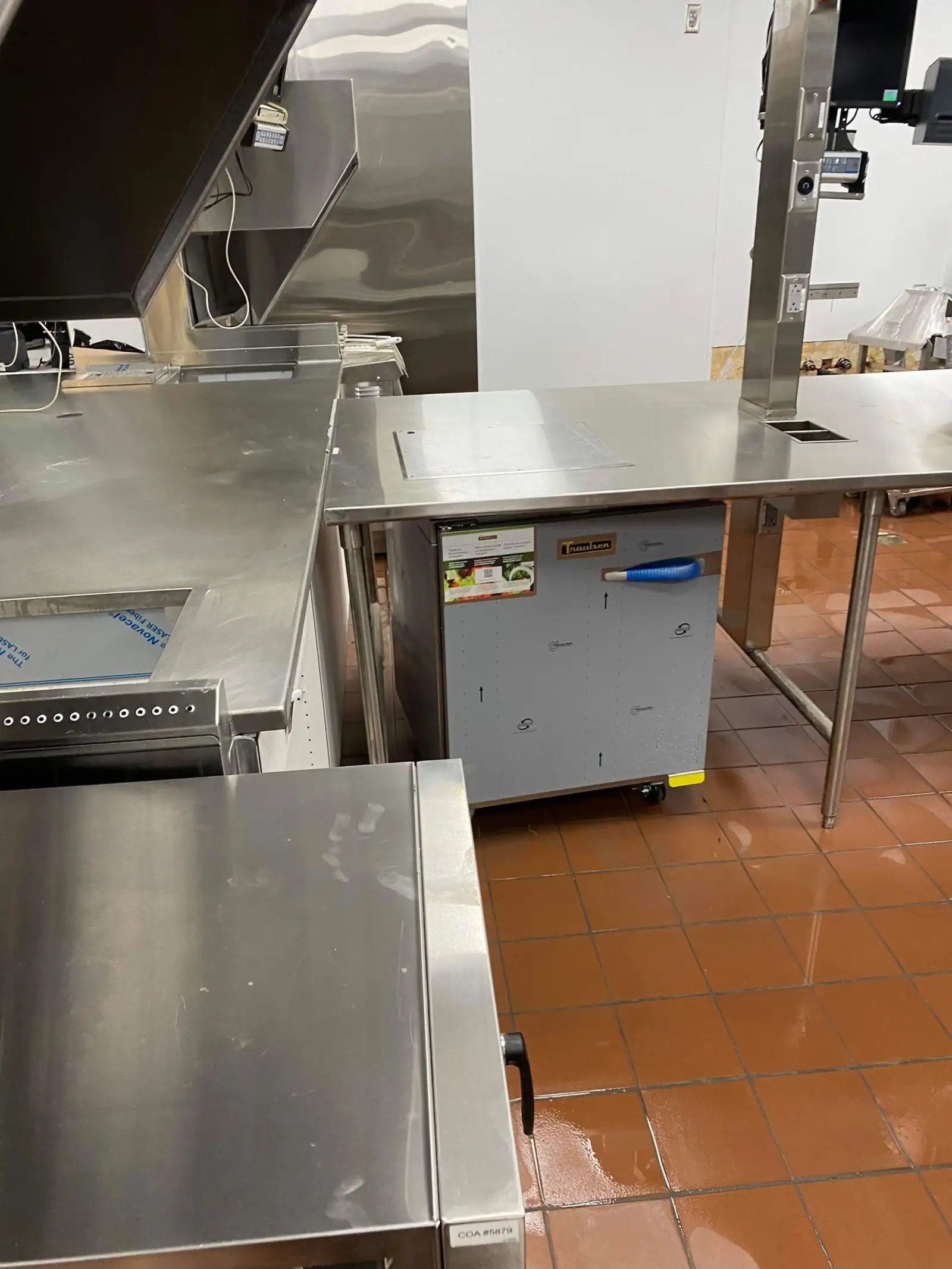 Stainless steel prep equipment and quarry tile floor cleaned in a restaurant kitchen