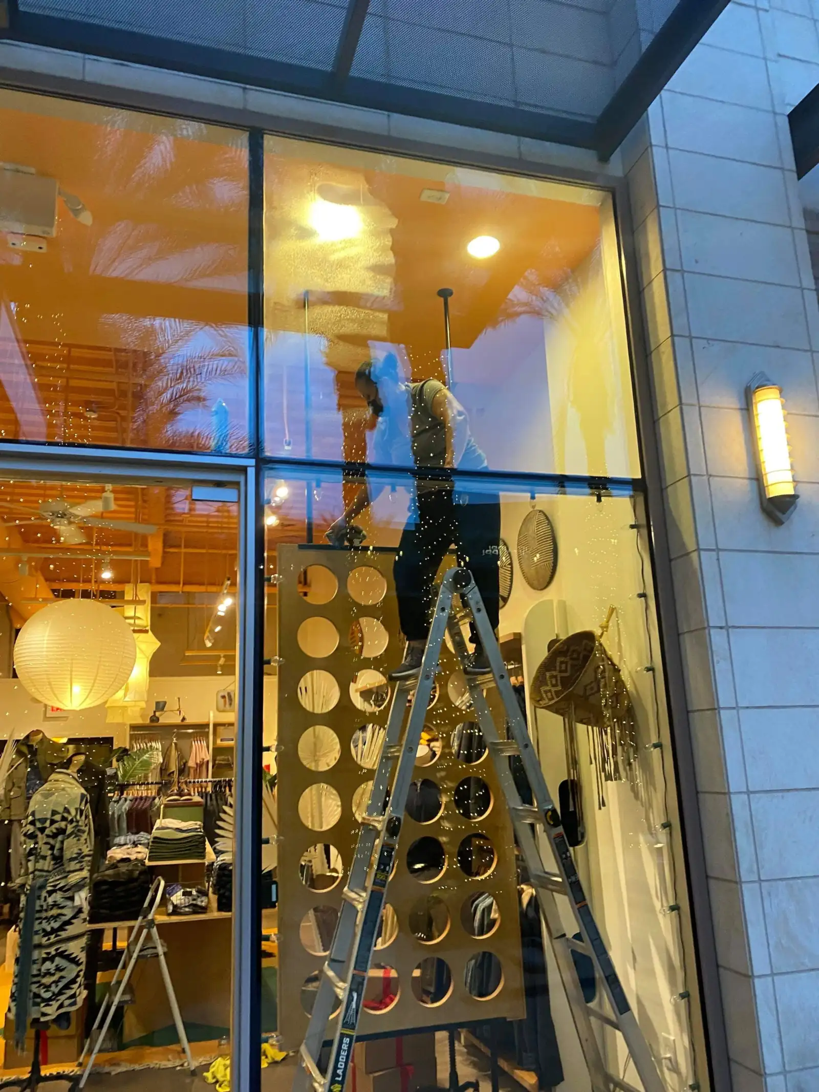 Technician cleaning interior storefront glass at a retail location